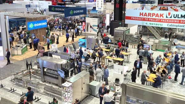 An aerial view of a trade show floor where companies display machinery and products in their booths.