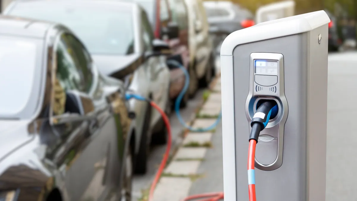 Close up of EV charger with cars parked in background