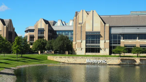 A building in front of a pond with the sign "Medtronic" on a stone wall.