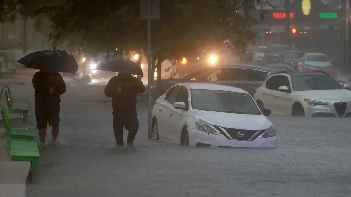 Flooding on a road with pedestrians holding umbrellas