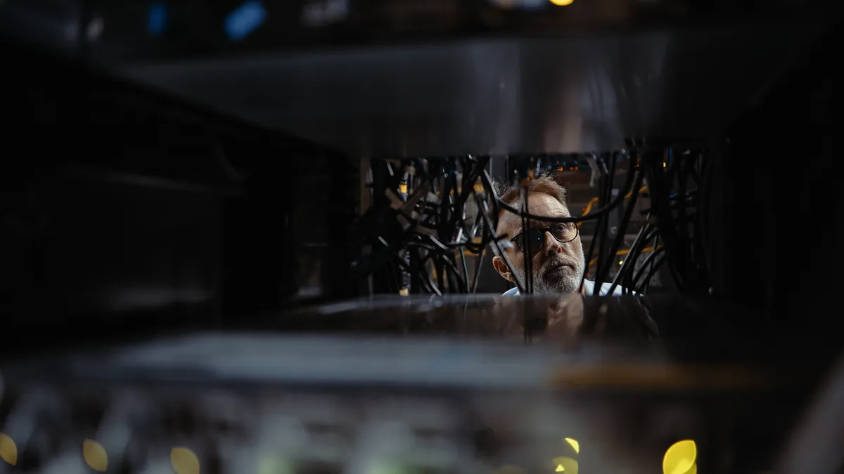 data center system administrator monitoring data cables in a server room