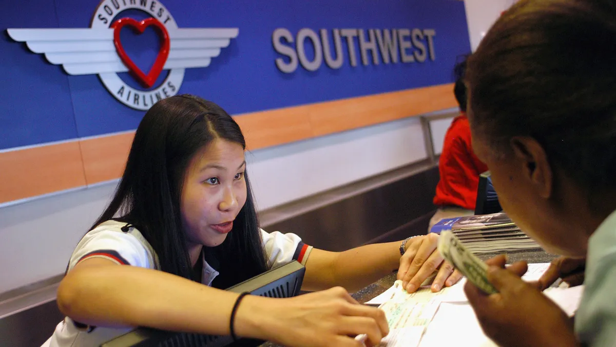 Southwest Airlines employee Agnes Chu of Oakland, California assists passenger Lois Ryals of Philadelphia, Pennsylvania at Philadelphia International Airport May 10, 2004 in Philadelphia, Pennsylvania