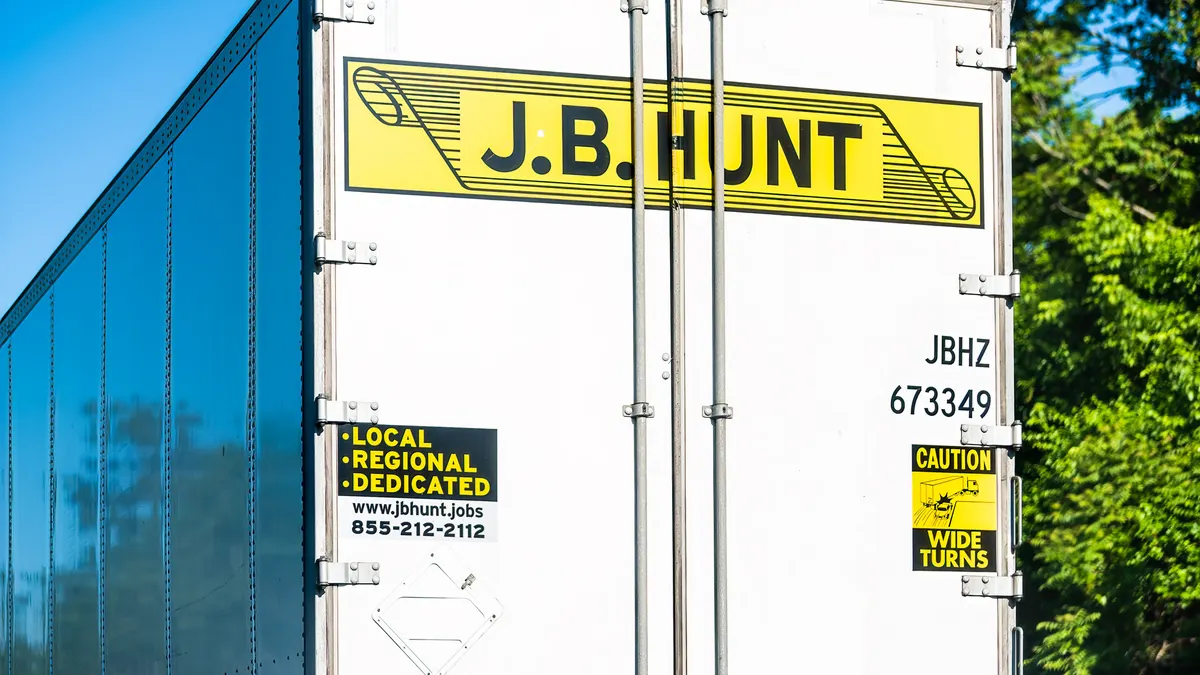 A J.B. Hunt trailer on I-66 in Virginia with tree branches in the background.