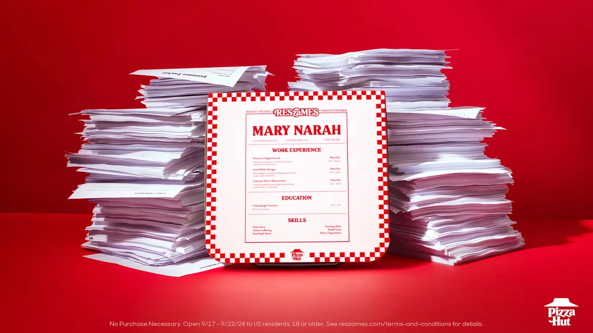 A Pizza Hut box next to stacks of resumes