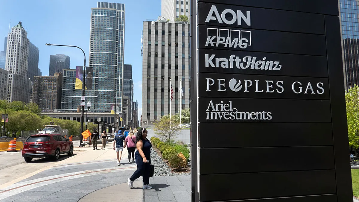 A view of downtown Chicago appears on the left while a black sign listing businesses, including Aon, appears closely in the foreground on the right.