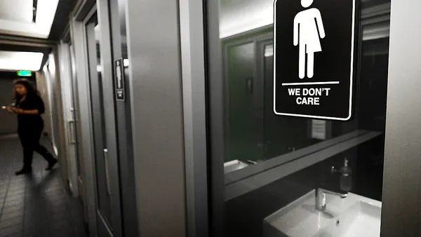 Door to gender-neutral restroom with sign reading "We Don't Care"