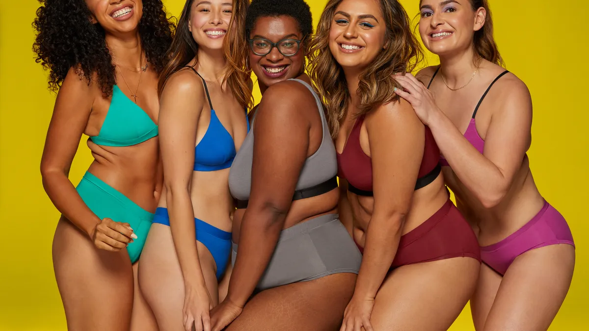 A group of five people gathered together wearing matching sets of underwear and bras in different colors.