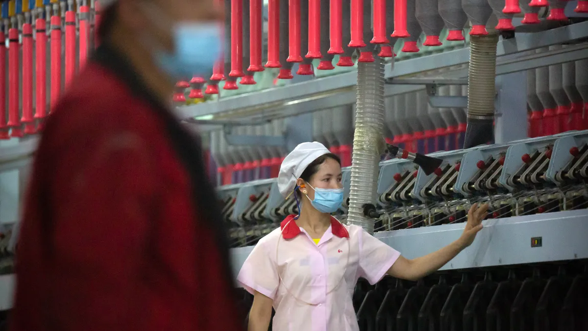 A worker checks machines processing cotton  in a factory.