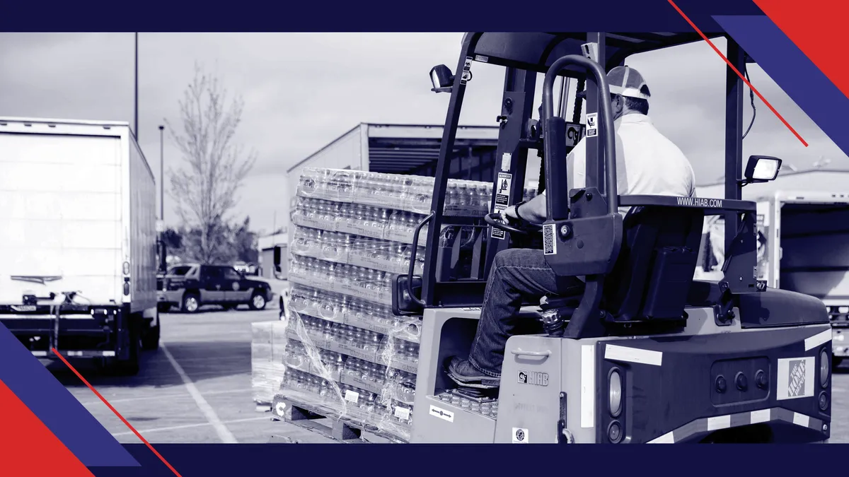 A man drives a forklift with water bottles.