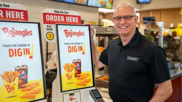 A man stands in front of two self-order kiosks at Bojangles.