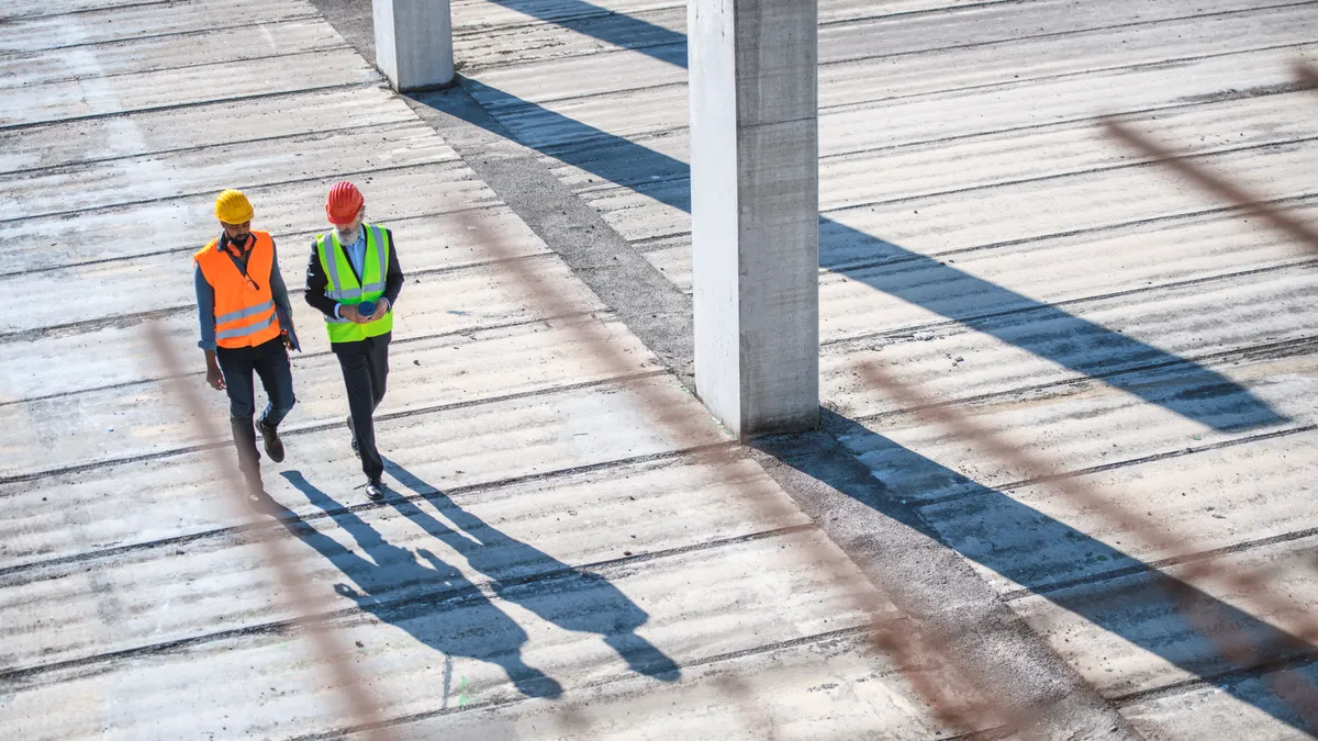 An aerial view of two people on a construction site, walking together.