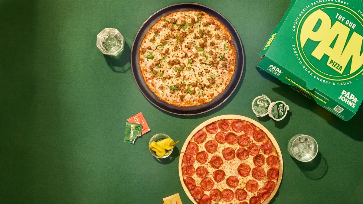 An image of two pan pizzas in front of a green background. On the right is a green pizza box.