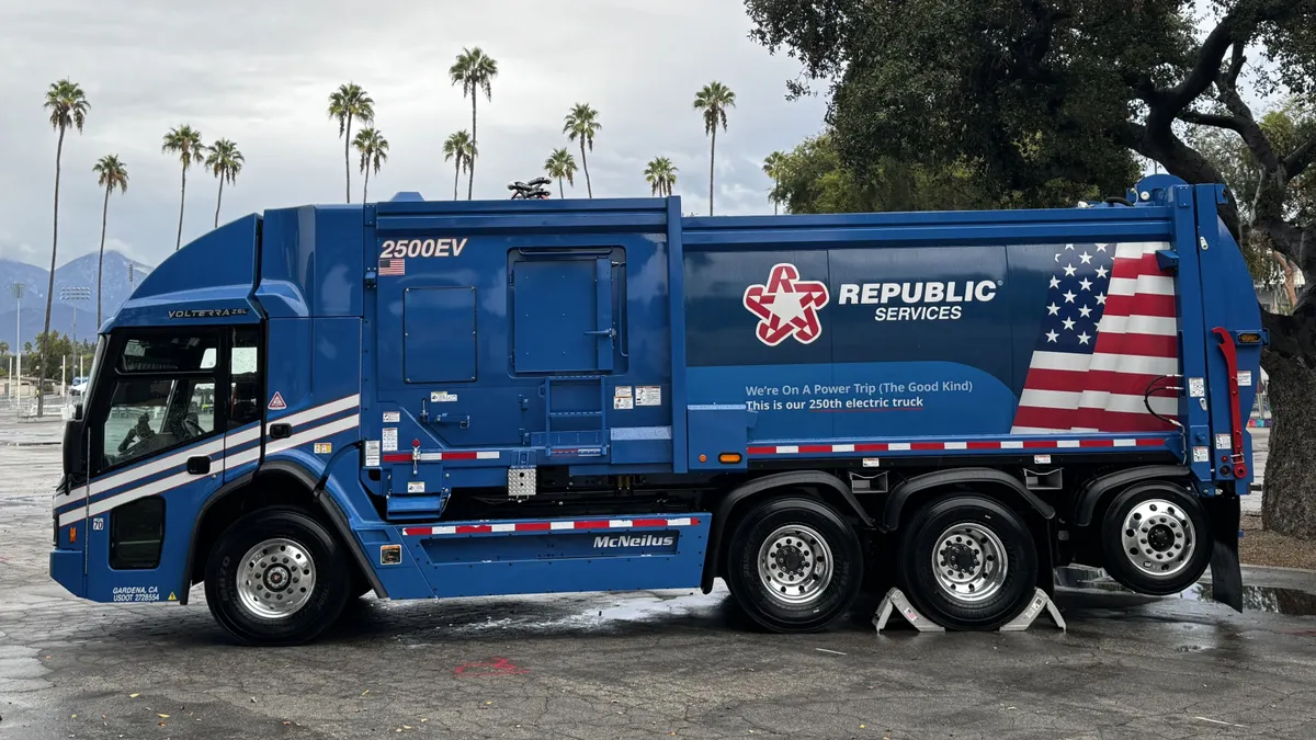 Side of a large refuse collection truck with Republic Services branding and the words "We're On A Power Trip (The Good Kind). This is our 250th electric truck." printed on the side.