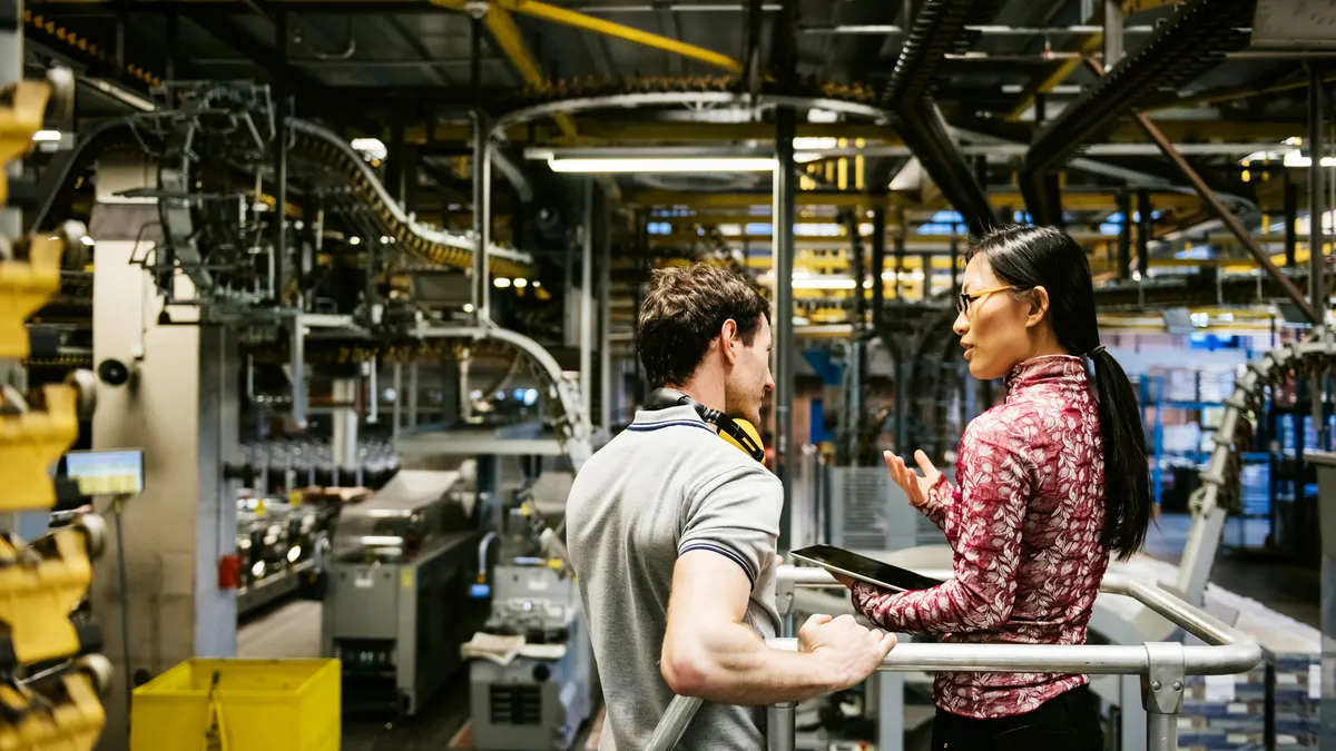 Two people talk in a manufacturing facility.