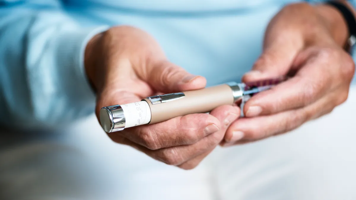 A close-up shot of a woman's hands, handling a syringe of insulin.