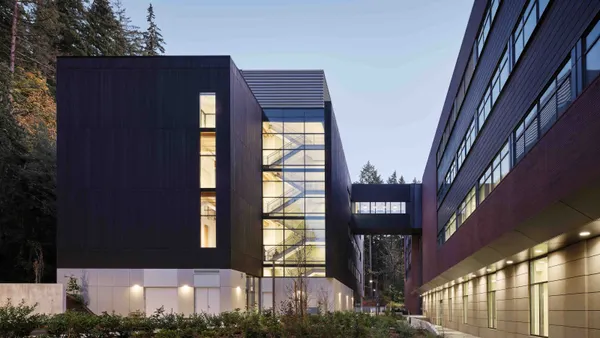 An image at dusk of a well-lit building surrounded by trees.