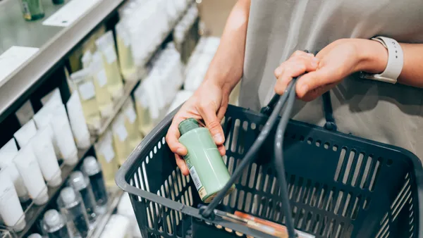 A person in a store places a cosmetic product into a shopping basket