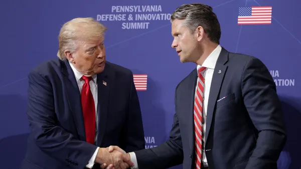 Two people in blue business suits and red ties shaking hands.