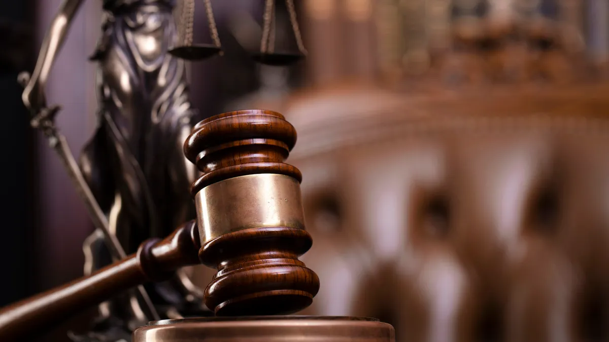 Judge’s gavel, Themis sculpture and collection of legal books on the brown background.