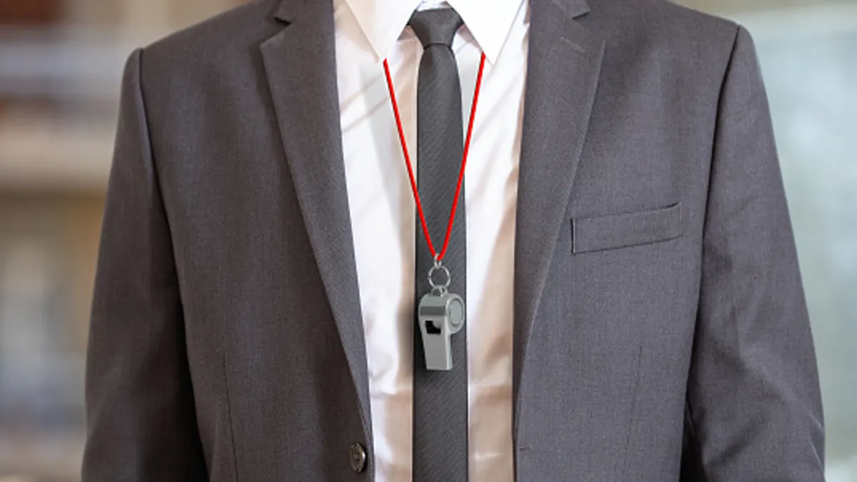 Person in suit wearing a whistle with red string.