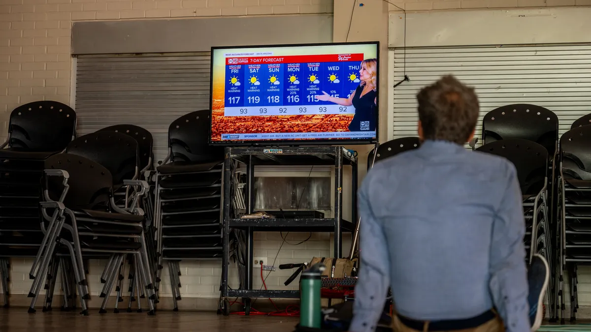 A person faces a television in an empty room