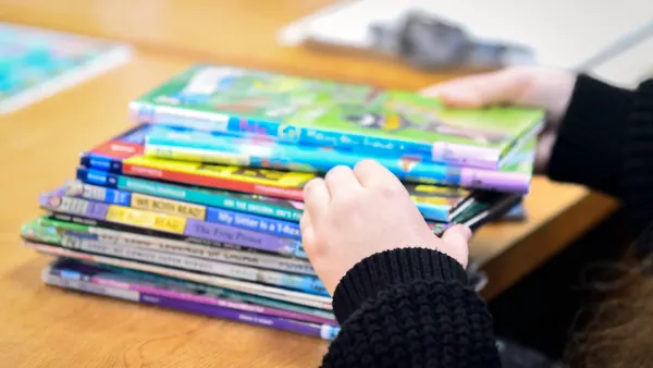 Image of a librarian's hands as she sorts through a pile of children's books that are out of focus.