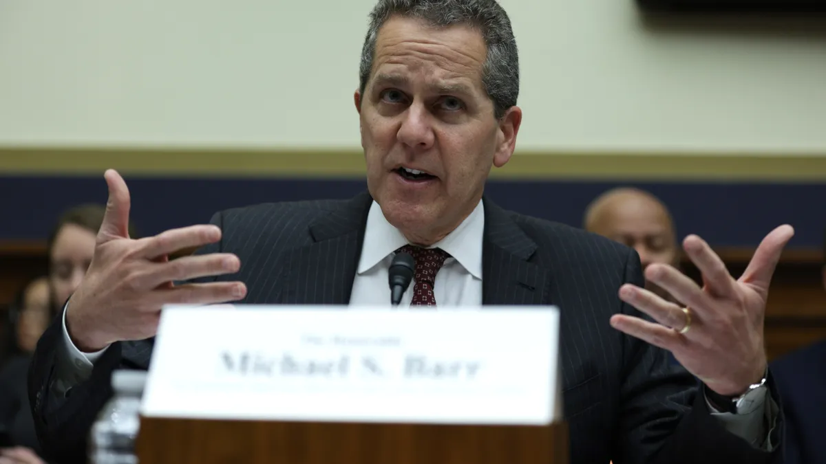 Michael Barr, Federal Reserve Board official, speaks during a Congressional hearing as other people sit behind him.