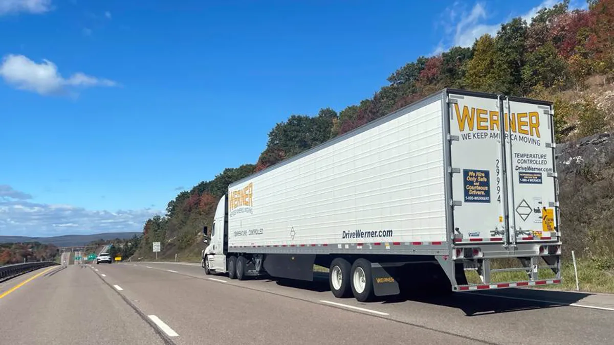 A Werner tractor-trailer on the interstate near a passenger vehicle.