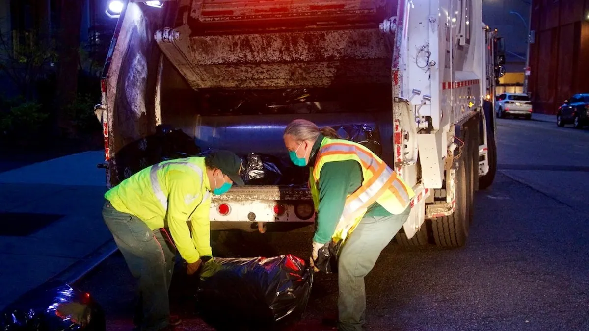 NYC Sanitation workers load waste into a collection truck