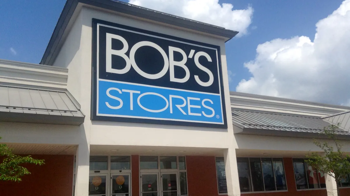 White puffy clouds against a blue sky, behind a store with a blue and white banner.