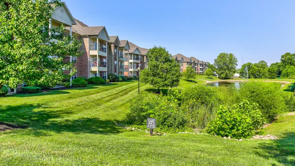 Garden apartments next to grass, trees and a pond.