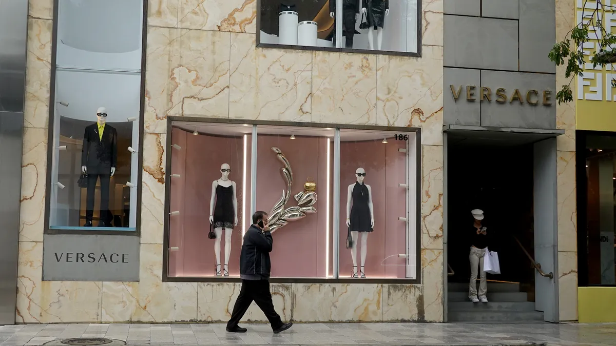 A person walks in front of a Versace storefront.