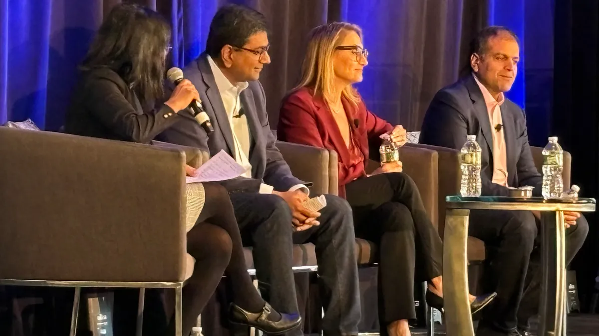 Three technology executives answer questions about shadow IT and multivendor AI strategy on stage during a panel discussion moderated by a woman.