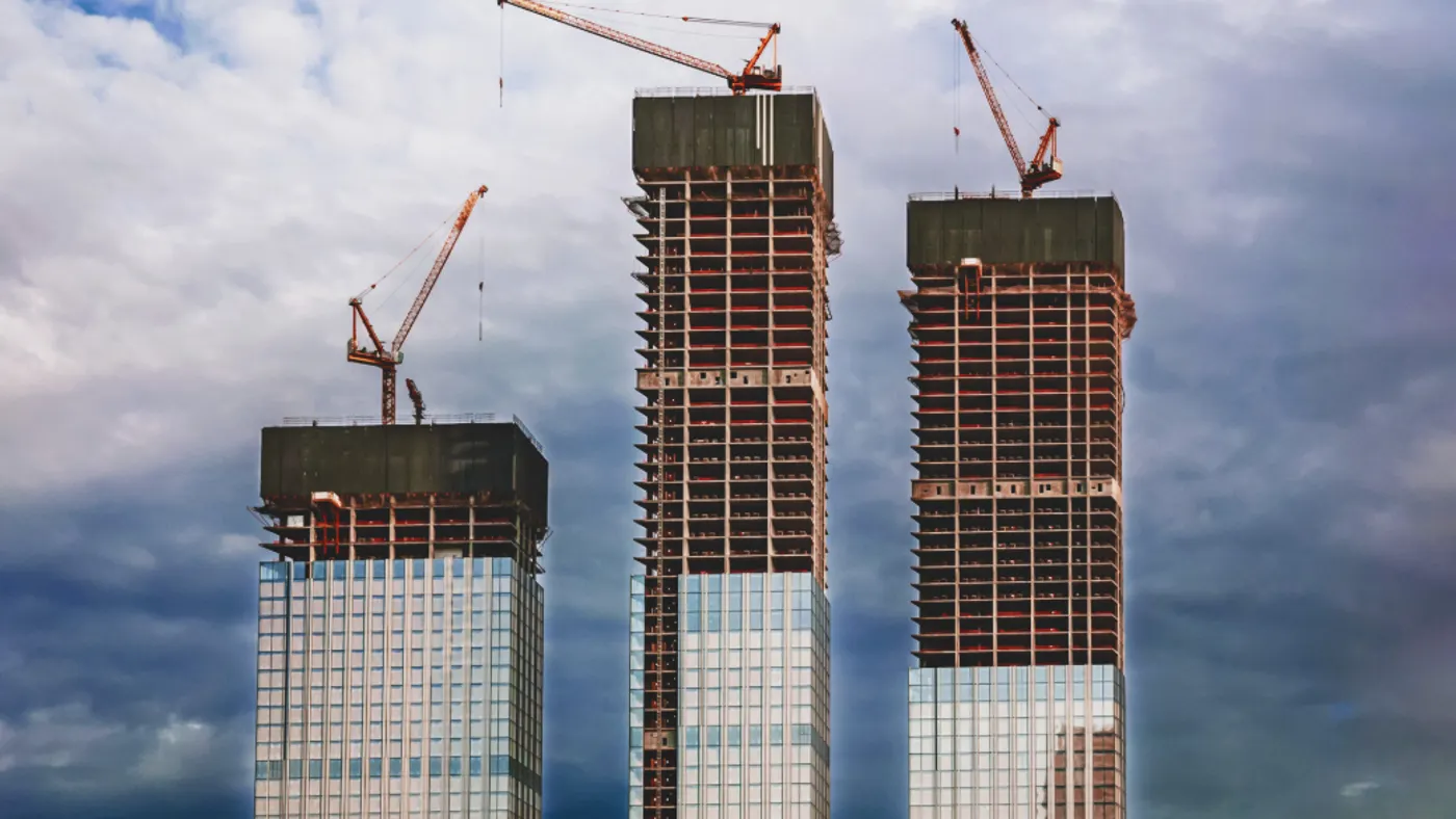 skyscrapers under construction, modern city buildings against dark stormy sky.