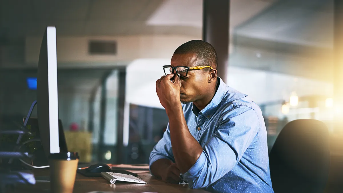 Shot of a young businessman experiencing stress during late night at work.