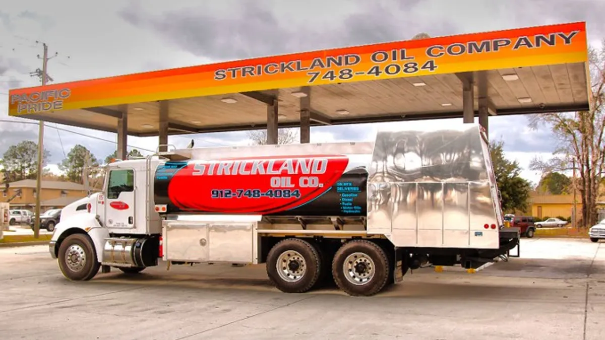 A photo of a tanker in front of a gas canopy with Strickland Oil on it.