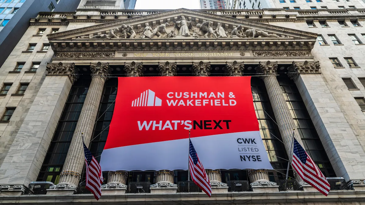 The New York Stock Exchange facade with a large ad that reads "Cushman & Wakefield, What's Next." 