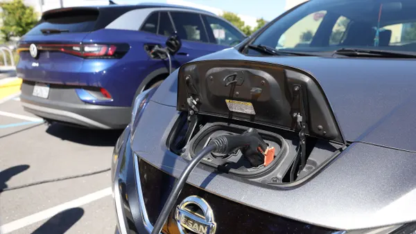 Nissan and Volkswagen electric cars sit parked at a Charge Point EV charging station.
