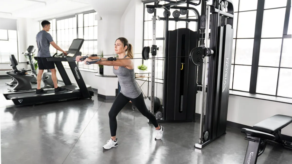 2 People working out in a gym on different gym equipment.