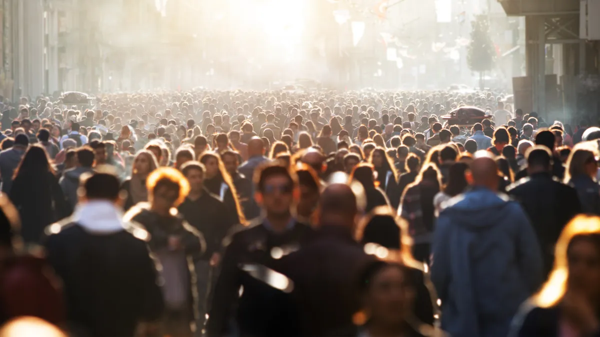 Blurred image of a crowd of people walking in the streets of a city