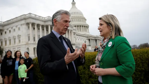 A man speaks with a woman with the U.S. Capitol building in the background.