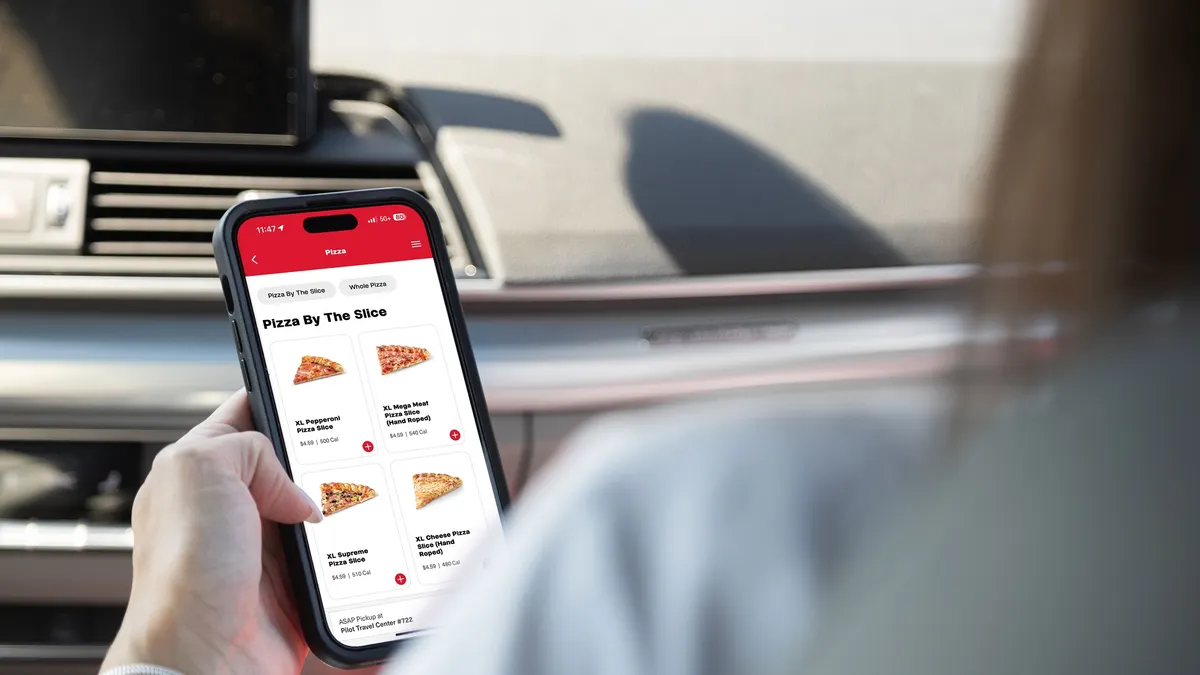 A photo of a a hand holding a mobile phone. The phone shows an app that says "Pizza by the slice. Pepperoni slice, mega meat pizza slice, supreme pizza slice, cheese pizza slice."