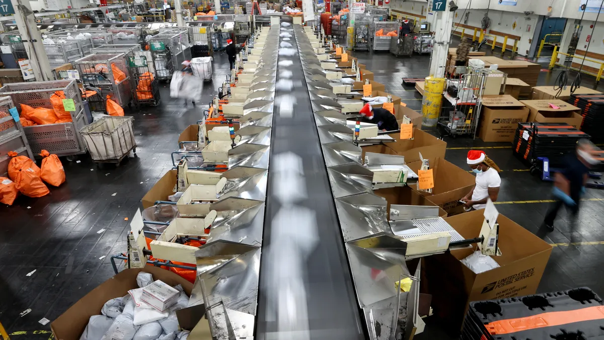 U.S. Postal Service employees work while sorting parcels for distribution inside the Los Angeles Mail Processing & Distribution Center, the largest in the United States, on November 22, 2021.