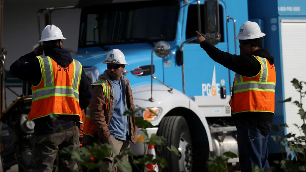 Pacific Gas and Electric workers in front of a PG&E truck.