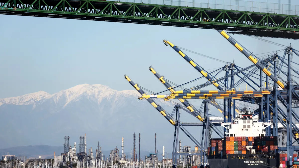 Shipping containers are stacked on a container ship at the Port of Los Angeles, as a truck passes above in front of the snow-capped San Gabriel Mountains, on February 7, 2023 in Los Angeles.