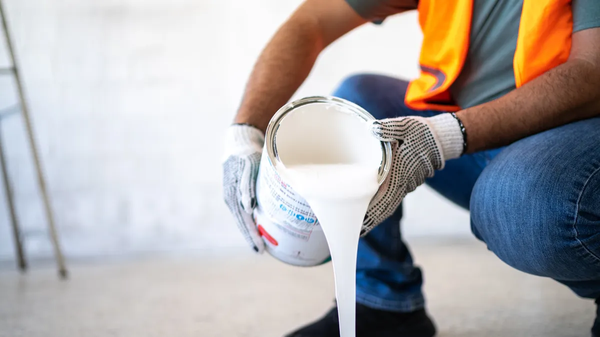 Painter/construction worker pouring paint indoors