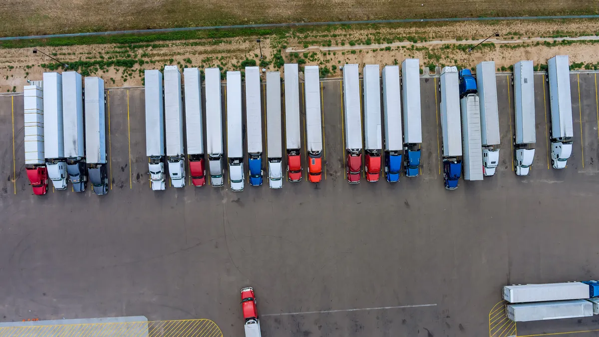 Trucks stand in a row at the rest area on the highway in aerial view.