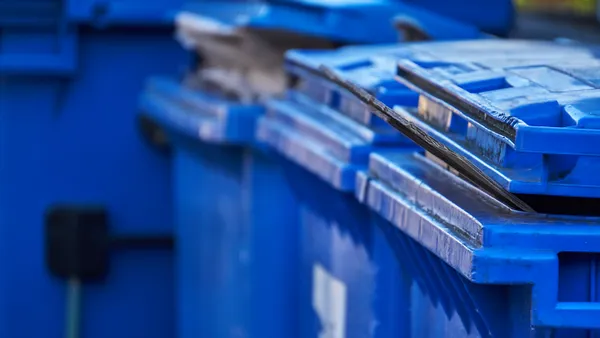 four blue recycling carts stand next to each other