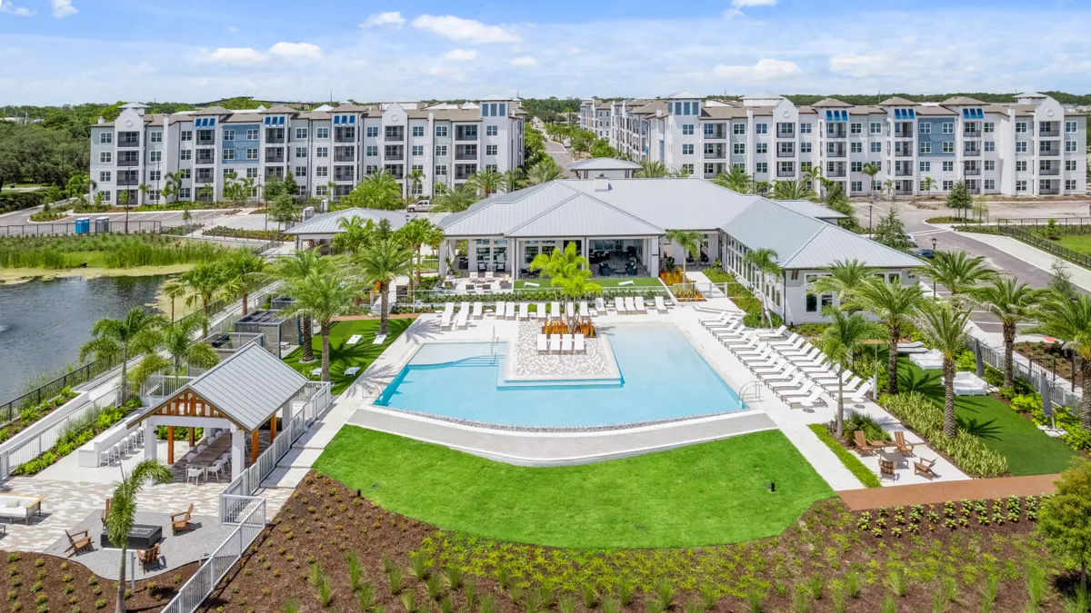 Aerial shot of an apartment property with a pool and trees in the clubhouse.