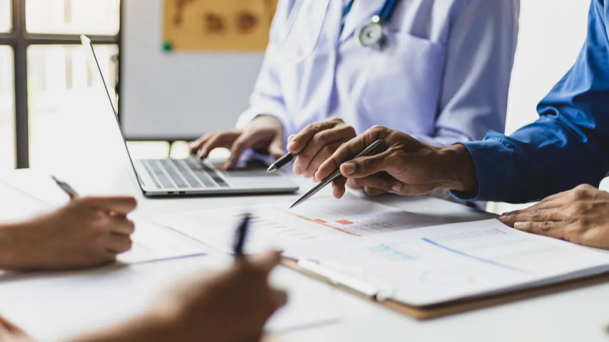 Team, medical analysts and doctors consulting with paperwork of graphs, data and charts in hospital conference room.